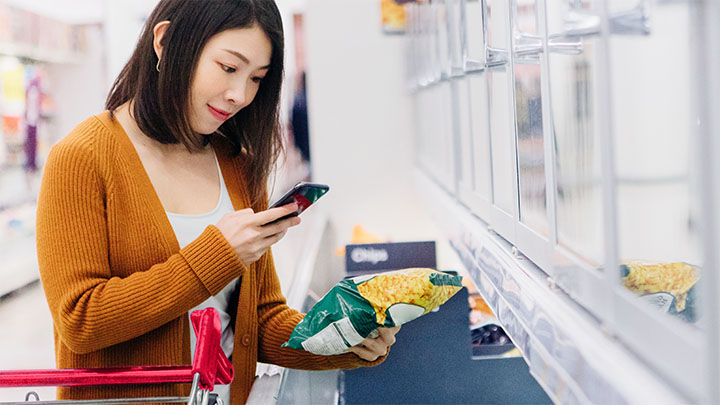 一位亚洲女性用智能手机在百货商场购买冷冻食品
